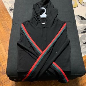 Black sweater with red and green striped sleeve.